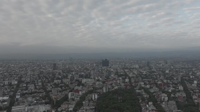 Aerial drone flying forward over M&eacute;xico City urban sprawl at sunrise with altocumulus clouds and hazy sky. Shot in D-Log M