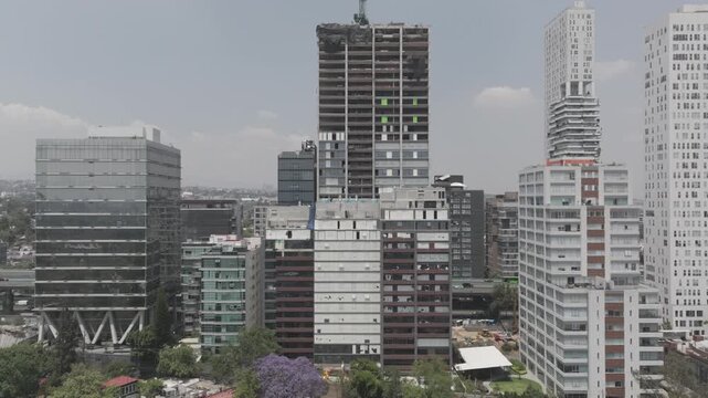 Aerial drone hovering in front of San &Aacute;ngel skyline with skyscrapers and building under construction in M&eacute;xico City. Shot in D-Log M