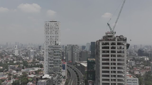 Aerial drone hovering over Perif&eacute;rico highway with traffic and skyscraper under construction in M&eacute;xico City. Shot in D-Log M