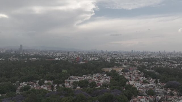Aerial drone flying forward over south M&eacute;xico City with cloudy sunset sky, Paseo de la Reforma skyline and Torre Mitikah. Shot in D-Log M