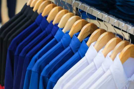 Row of neatly organized white and blue shirts hanging on a rack in a retail store