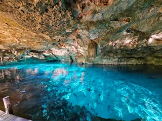 Fototapeta premium Underground cenote with bright blue water and hanging limestone formations in Yucatan Mexico