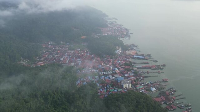 Aerial perspective captures Pulau Pangkor, morning mist veiling fishing boats near the jetty.