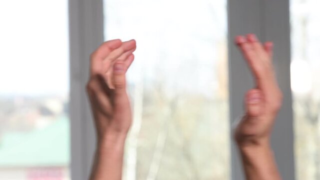 Man clapping hands near window indoors, closeup