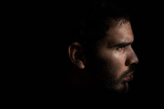 Dramatic side profile of a man in low key lighting.