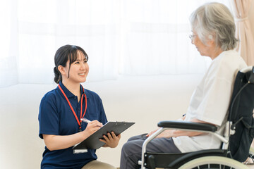 Obraz premium A female caregiver interviews a senior woman in a wheelchair.
