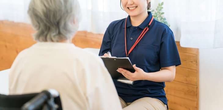 A female caregiver interviews a senior woman in a wheelchair.
