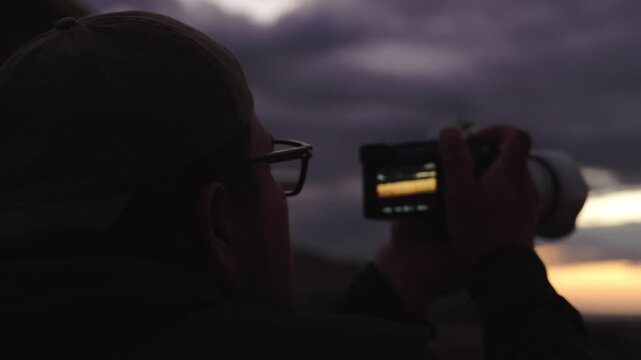 Photographer shooting dramatic sunset with mirrorless camera