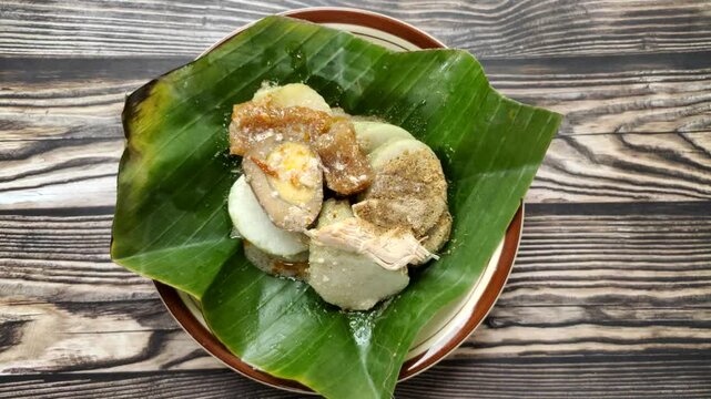 Lontong opor is a traditional Indonesian dish consisting of slices of lontong topped with a savory chicken opor sauce. It is served with shredded chicken, krecek, and pindang egg.