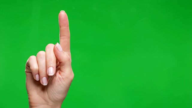 A close-up of a female hand with the index finger pointing up against a green screen, indicating direction or number one.