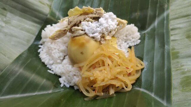 A delicious Nasi Liwet served on fresh banana leaves. Nasi Liwet Solo is a traditional dish from Surakarta or Solo, Central Java, Indonesia, consisting of fragrant rice cooked with coconut milk.
