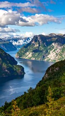 Obraz premium A scenic vista showcasing a winding fjord, flanked by lush green cliffs. Blue skies and fluffy clouds enhance the natural beauty