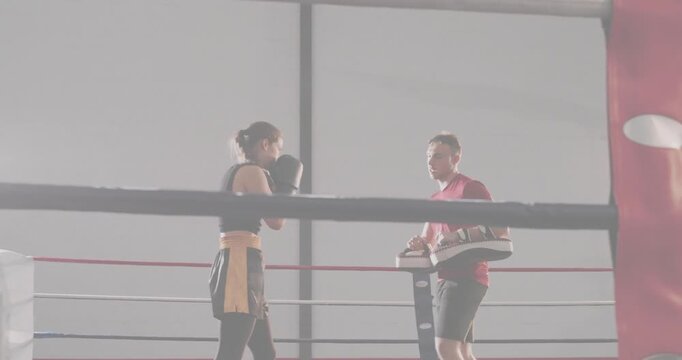 Woman boxer stepping into guard starting drill, punching, turning kick while trainer moving pads