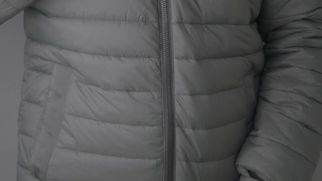 Close-up shot of hands zipping up winter puffer jacket on person.