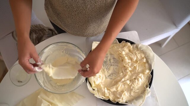 Top view woman prepares traditional Balkan phyllo cheese pie