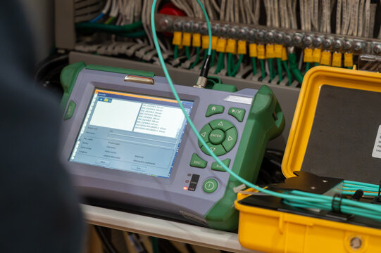 Two technicians measure the signal level in the fiber optic cable. Serving a central router in a server room. Two people work in a modern data center.