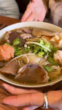 Close Up of Spicy Vietnamese Bun Bo Hue Noodle Soup Being Served
