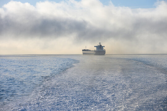 Bulk carrier cargo ship in Puget Sound on a foggy morning with air full of exhaust and pollution, global shipping of trade goods worldwide, import and export in the international economy
