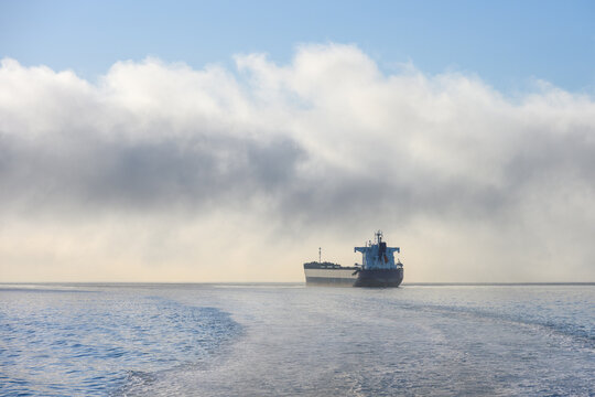 Bulk carrier cargo ship in Puget Sound on a foggy morning with air full of exhaust and pollution, global shipping of trade goods worldwide, import and export in the international economy
