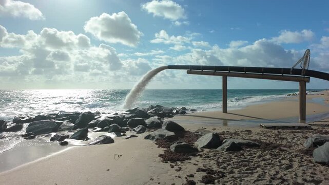 Sand being deposited via this pipe on the beach for a beach reclamation project after being moved from above a jetty where it has piled up at Ocean Inlet Beach in Boynton Beach Florida