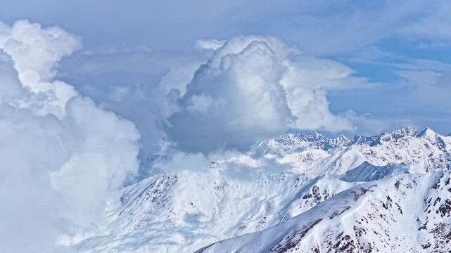 Aerial view of snowy mountain peaks above clouds in Nauders Austria, epic alpine winter landscape