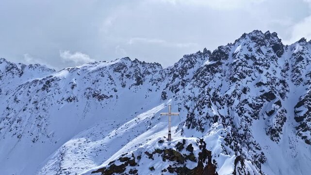 Aerial fly over snowy mountain peaks with summit marker in Nauders Austria, pure alpine winter nature landscape