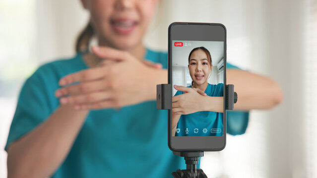 Young adult woman asia people anti aging expert modern nurse live talk video call selfie camera mobile phone app mental health care Online digital virtual asian vlogger filming hand wrist pain physio.
