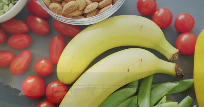 Top-down camera shifting, showing food, bananas moving, peas appearing, nut bowl, pepper entering