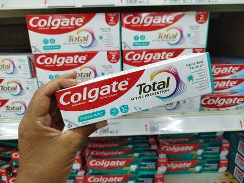 KUALA TERENGGANU MALAYSIA- APRIL 07. 2026  Close-up of hand holding Colgate Total Active Prevention Fresh Mint toothpaste box in supermarket aisle, highlighting oral care branding and consumer choice