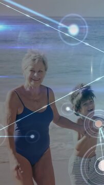 Vertical video: Senior woman and boy strolling shoreline, motion sparking tech overlay showing bond