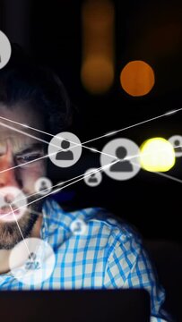 Vertical video: Bearded man using laptop, incoming data causing animated tech overlay over face
