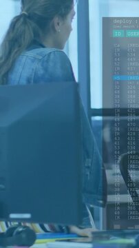 Vertical video: Woman at desk watching deploy terminal appearing and verifying deploy status for IT