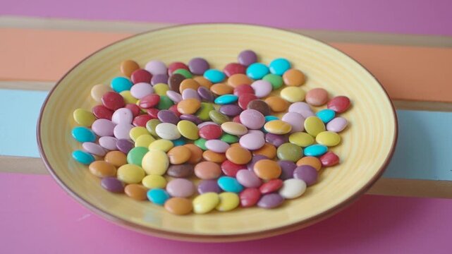 Child hand pick colorful candies arranged on a plate 
