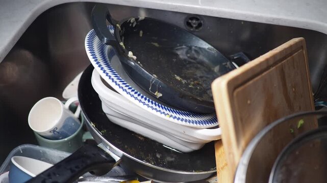 Dirty dishes stack in sink after meal preparation