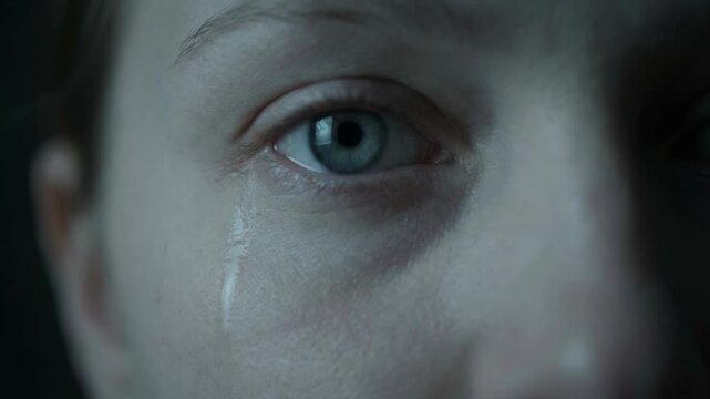 Spooky blonde girl in worn black and white photo concept. Close up of a blue eye with a tear falling down the cheek expressing emotion and sadness