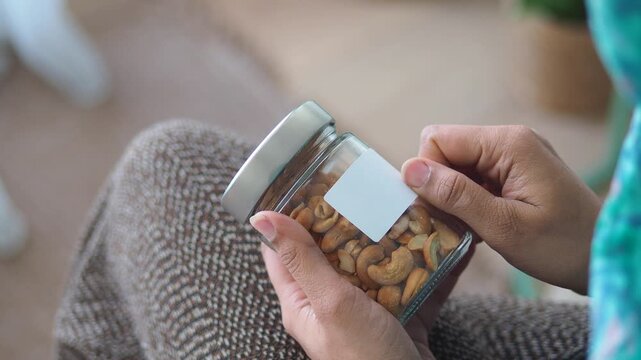 Hands putting a label on a jar of cashews in a living room