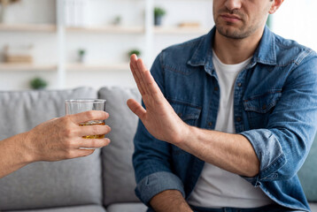 Fototapeta premium Man refusing a glass of alcohol with a stop gesture to quit drinking for sobriety