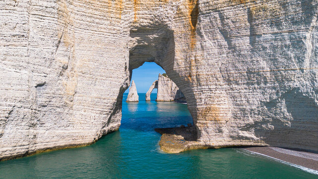 Framed perspective of the Needle and Aval Arch through the massive Manneporte natural arch in Etretat, Normandy, France