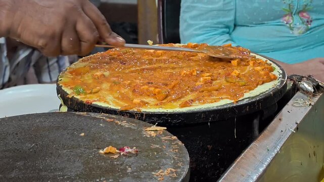 Indian street food vendor preparing dosa on hot tawa