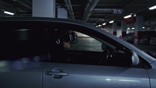 Futuristic man wearing vr glasses driving a car in an underground parking lot
