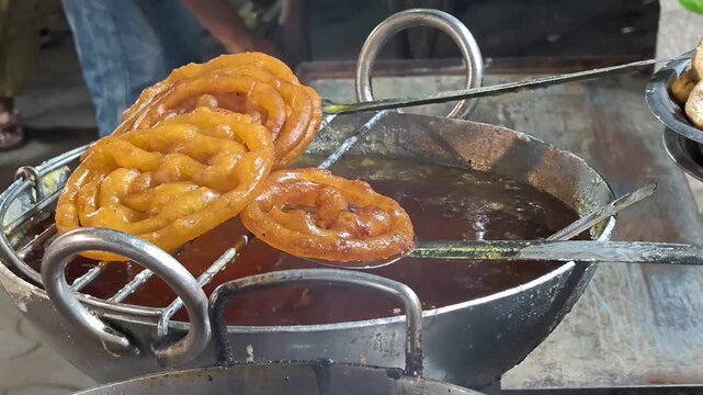 Indian sweet jaleba being deep fried and soaked in sugar syrup at street market
