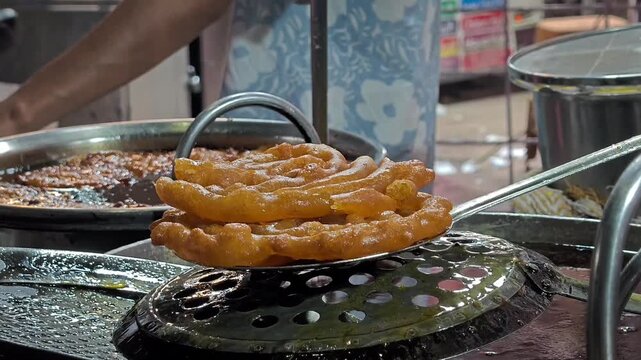 Indian sweet jaleba being deep fried and soaked in sugar syrup at street market