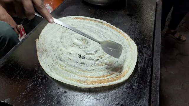 Crispy plain dosa on a hot flat tawa griddle