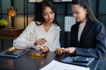 Fototapeta premium Two Asian businesswoman trading gold bar together
