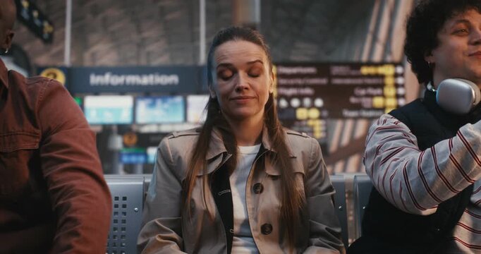 Feeling Uneasy In Restless Airport Atmosphere, Young Woman Remains Calm Escape Surrounding Stress. Body Language Suggests Flight Response Crowds Energy as Desperately Waits For Boarding Call.