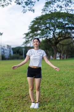 Young woman exercising outdoors in lush parkland