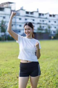 Young woman celebrating success with arms raised outdoors