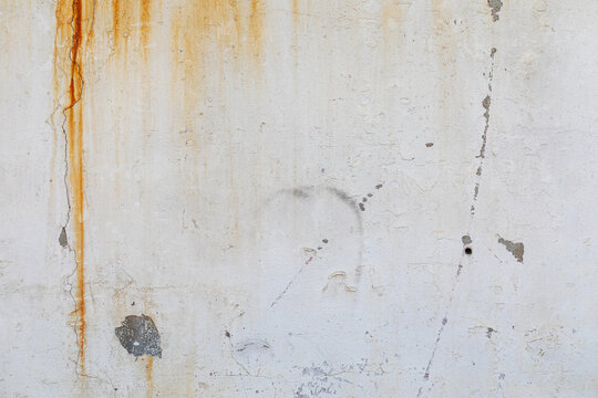old weathered white wall with orange rust drips and vertical cracks