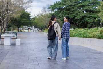 Obraz premium Two young Asian women friends walking hand in hand outdoors