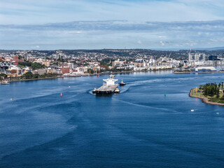 Fototapeta premium Aerial drone view of a large cargo ship being escorted by tug boats through Newcastle Harbour in New South Wales, Australia.
